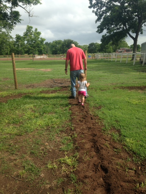 Kendyll following in her daddy's foot steps as he taps down the dirt on the new water lines.